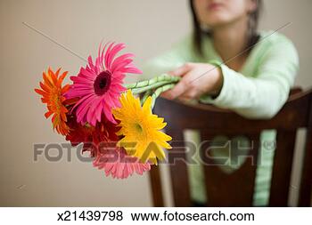 Stock Photo - young woman holding 
flowers sitting 
on chair, focus 
on flowers. fotosearch 
- search stock 
photos, pictures, 
images, and photo 
clipart