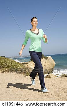 Stock Image - young woman running 
on beach, smiling, 
smiling. fotosearch 
- search stock 
photos, pictures, 
images, and photo 
clipart