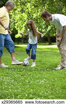 Stock Image - girl (7-9) playing 
football in park 
with father and 
grandfather. fotosearch 
- search stock 
photos, pictures, 
images, and photo 
clipart