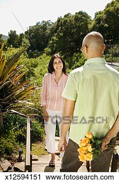 Stock Photography - mid adult man 
and woman in botanical 
garden,  man hiding 
bunch of. fotosearch 
- search stock 
photos, pictures, 
images, and photo 
clipart