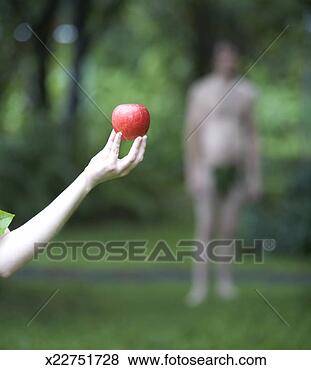 Stock Photo - woman holding 
apple in forest, 
man in background 
(focus on apple). 
fotosearch - search 
stock photos, 
pictures, images, 
and photo clipart