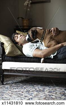 Stock Photography - young man and 
dog lying on sofa, 
dog licking man's 
face. fotosearch 
- search stock 
photos, pictures, 
images, and photo 
clipart