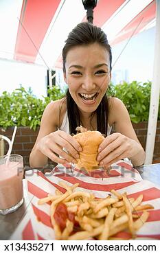 Stock Photography - woman holding 
hamburger in caf 
. fotosearch - 
search stock photos, 
pictures, images, 
and photo clipart