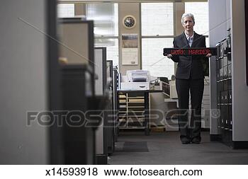 Stock Photo - woman standing 
in office corridor 
holding led sign 
saying 'work. 
fotosearch - search 
stock photos, 
pictures, images, 
and photo clipart