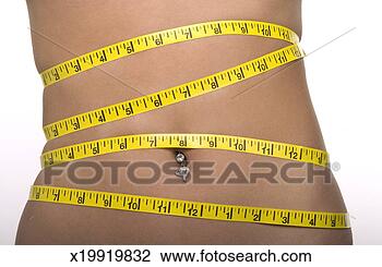 Stock Photo - woman with tape 
measure around 
abdomen with belly 
button piercing. 
fotosearch - search 
stock photos, 
pictures, images, 
and photo clipart