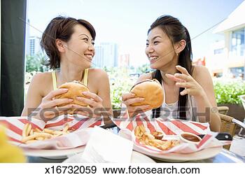 Stock Photograph - women holding 
hamburgers, smiling. 
fotosearch - search 
stock photos, 
pictures, images, 
and photo clipart