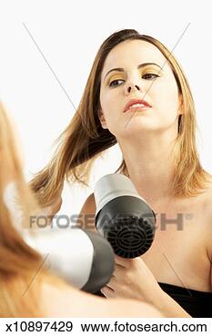 Stock Photograph - young woman in 
front of mirror, 
drying hair with 
hair dryer. fotosearch 
- search stock 
photos, pictures, 
images, and photo 
clipart