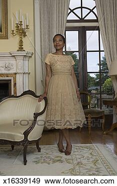 Stock Photograph - mature woman standing 
by chair, smiling. 
fotosearch - search 
stock photos, 
pictures, images, 
and photo clipart
