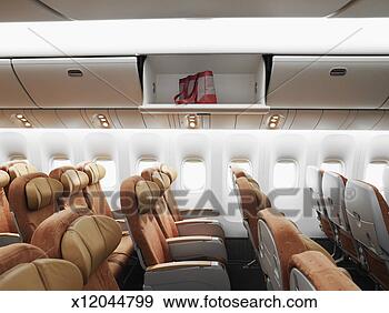 Stock Photograph - empty airplane 
interior, bag 
left in overhead 
bin, side view. 
fotosearch - search 
stock photos, 
pictures, images, 
and photo clipart