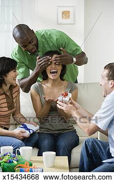 Stock Photo - four young people 
sitting in living 
room at home, 
 one man offering. 
fotosearch - search 
stock photos, 
pictures, images, 
and photo clipart