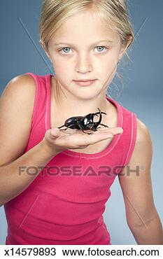 Stock Photo - girl (8-9) holding 
large black beetle, 
portrait. fotosearch 
- search stock 
photos, pictures, 
images, and photo 
clipart