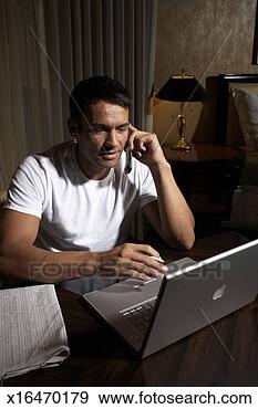 Stock Photograph - mid adult man 
using laptop and 
mobile phone in 
room. fotosearch 
- search stock 
photos, pictures, 
images, and photo 
clipart