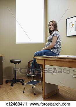 Stock Photography - pregnant teenage 
girl (16-17) sitting 
on exam table 
in medical. fotosearch 
- search stock 
photos, pictures, 
images, and photo 
clipart