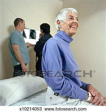 Stock Photo - senior woman in 
doctors office 
sitting on bed, 
 doctors looking 
at. fotosearch 
- search stock 
photos, pictures, 
images, and photo 
clipart