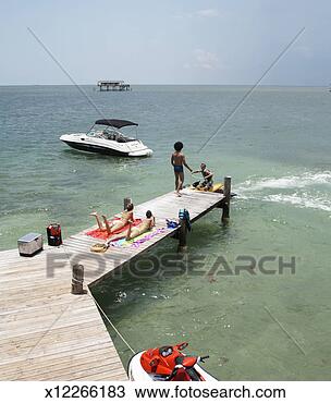 Stock Photo - two women relaxing 
on jetty,  man 
helping another 
man from jet boat. 
fotosearch - search 
stock photos, 
pictures, images, 
and photo clipart