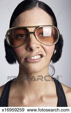 Stock Photograph - young woman wearing 
sunglasses and 
earmuffs,  pulling 
facial. fotosearch 
- search stock 
photos, pictures, 
images, and photo 
clipart