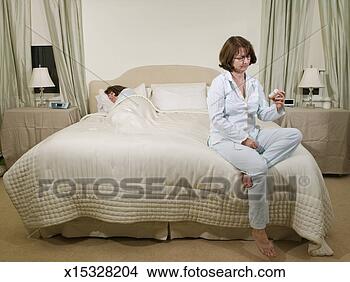 Stock Photo - mature woman sitting 
on bed looking 
at bottle of pills, 
 other woman. 
fotosearch - search 
stock photos, 
pictures, images, 
and photo clipart