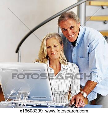 Stock Photograph - elderly woman 
working on a computer 
with an elderly 
man standing. 
fotosearch - search 
stock photos, 
pictures, images, 
and photo clipart