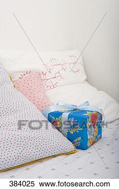Banco de Imagem - presente,  sentando, 
 cama,  entre, 
 travesseiros. 
fotosearch - busca 
de fotos, imagens 
e clipart