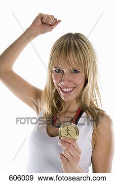 Arquivo Fotográficos - mulher,   segurando, 
  ouro,   medalha, 
  levantamento, 
  punho. fotosearch 
- busca de fotos, 
imagens e clipart