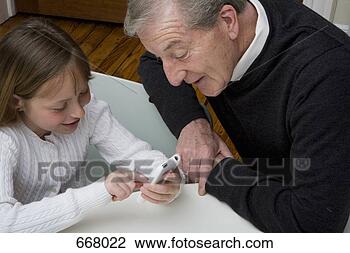 Banco de Imagem - neta,  usando, 
 eletrônico,  
dispositivo,  
enquanto,  avô, 
 relógio. fotosearch 
- busca de fotos, 
imagens e clipart