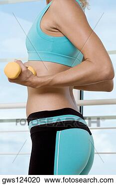 Stock Photography - mid section view 
of a young woman 
exercising with 
dumbbells. fotosearch 
- search stock 
photos, pictures, 
images, and photo 
clipart