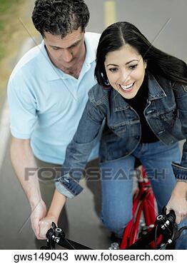 Stock Photo - high angle view 
of a mid adult 
man helping a 
mid adult woman 
ride a. fotosearch 
- search stock 
photos, pictures, 
images, and photo 
clipart