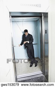 Stock Photograph - businessman standing 
in an elevator 
and looking at 
his wristwatch. 
fotosearch - search 
stock photos, 
pictures, images, 
and photo clipart