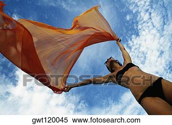 Stock Image - woman holding 
a orange colored 
fabric in the 
tropical breeze 
on the. fotosearch 
- search stock 
photos, pictures, 
images, and photo 
clipart
