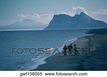 Stock Image - three people walking 
on the beach, 
rock of gibraltar, 
gibraltar, spain. 
fotosearch - search 
stock photos, 
pictures, images, 
and photo clipart