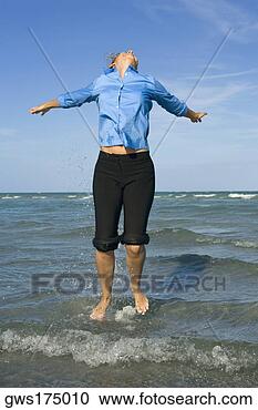 Arquivo de Fotografias - meio,  mulher, 
 pular,  praia, 
 braços,  estendido. 
fotosearch - busca 
de fotos, imagens 
e clipart