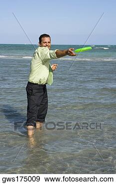 Stock Photograph - mid adult man 
playing with a 
plastic disc on 
the beach. fotosearch 
- search stock 
photos, pictures, 
images, and photo 
clipart