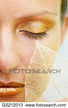Stock Photo - close up of a 
lady's face with 
golden make up 
and a skeletal 
leaf on. fotosearch 
- search stock 
photos, pictures, 
images, and photo 
clipart