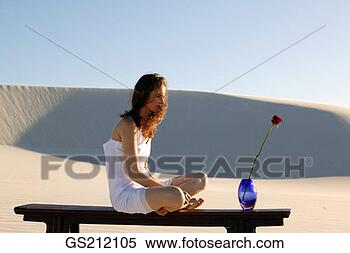 Stock Image - a lady sitting 
cross-legged beside 
a blue vase holding 
a single red. 
fotosearch - search 
stock photos, 
pictures, images, 
and photo clipart