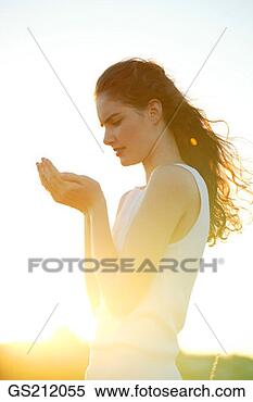 Stock Image - lady in the sunshine 
looking into her 
cupped hands. 
fotosearch - search 
stock photos, 
pictures, images, 
and photo clipart