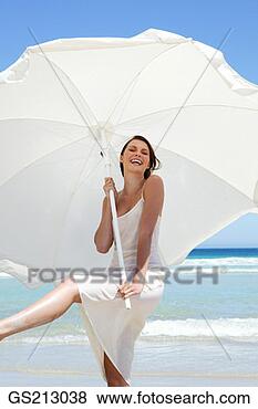 Stock Photo - smiling woman 
at the seafront, 
 standing under 
a white parasol. 
fotosearch - search 
stock photos, 
pictures, images, 
and photo clipart