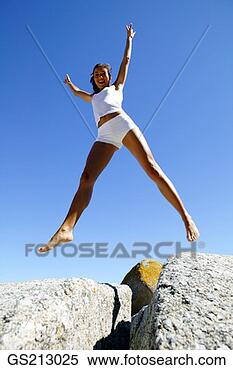 Stock Image - woman jumping 
across a gap between 
two boulders. 
fotosearch - search 
stock photos, 
pictures, images, 
and photo clipart