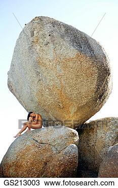 Stock Photo - woman in the nude 
sitting between 
two boulders. 
fotosearch - search 
stock photos, 
pictures, images, 
and photo clipart