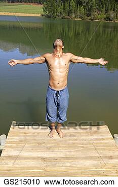 Stock Photography - man on the edge 
of a jetty with 
outstretched arms. 
fotosearch - search 
stock photos, 
pictures, images, 
and photo clipart