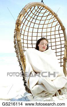 Stock Photo - woman curled up 
in a blanket asleep 
in a hanging wicker 
seat. fotosearch 
- search stock 
photos, pictures, 
images, and photo 
clipart