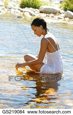 Stock Photo - woman in a wet 
sundress sitting 
in shallow water, 
looking downwards. 
fotosearch - search 
stock photos, 
pictures, images, 
and photo clipart