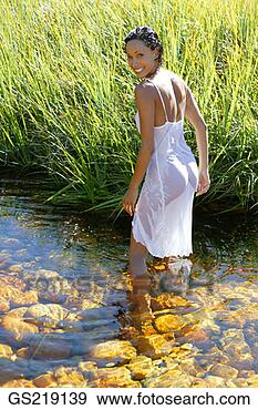 Stock Photograph - woman in a wet 
sundress paddling 
in a river, looking 
behind. fotosearch 
- search stock 
photos, pictures, 
images, and photo 
clipart