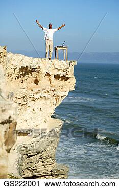 Stock Photography - man with outstretched 
arms on the edge 
of a cliff. fotosearch 
- search stock 
photos, pictures, 
images, and photo 
clipart
