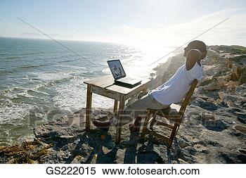 Stock Image - man relaxing at 
his desk on the 
edge of a cliff. 
fotosearch - search 
stock photos, 
pictures, images, 
and photo clipart