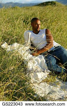 Stock Photo - dark-skinned bald 
man relaxing in 
the tall grasses. 
fotosearch - search 
stock photos, 
pictures, images, 
and photo clipart