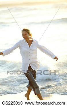 Stock Photo - woman walking 
on the strand 
with outstretched 
arms. fotosearch 
- search stock 
photos, pictures, 
images, and photo 
clipart