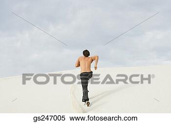 Stock Image - rear view of man 
running in sand. 
fotosearch - search 
stock photos, 
pictures, images, 
and photo clipart