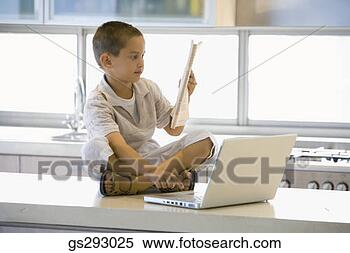 Stock Image - boy reading newspaper 
and using laptop. 
fotosearch - search 
stock photos, 
pictures, images, 
and photo clipart