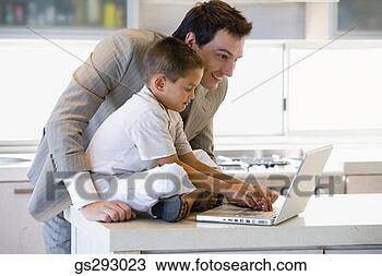 Stock Photo - father and son 
using laptop in 
kitchen. fotosearch 
- search stock 
photos, pictures, 
images, and photo 
clipart