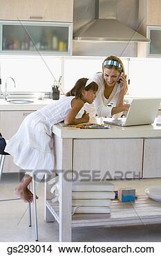 Stock Photo - mother and daughter 
in kitchen with 
cell phone and 
laptop. fotosearch 
- search stock 
photos, pictures, 
images, and photo 
clipart